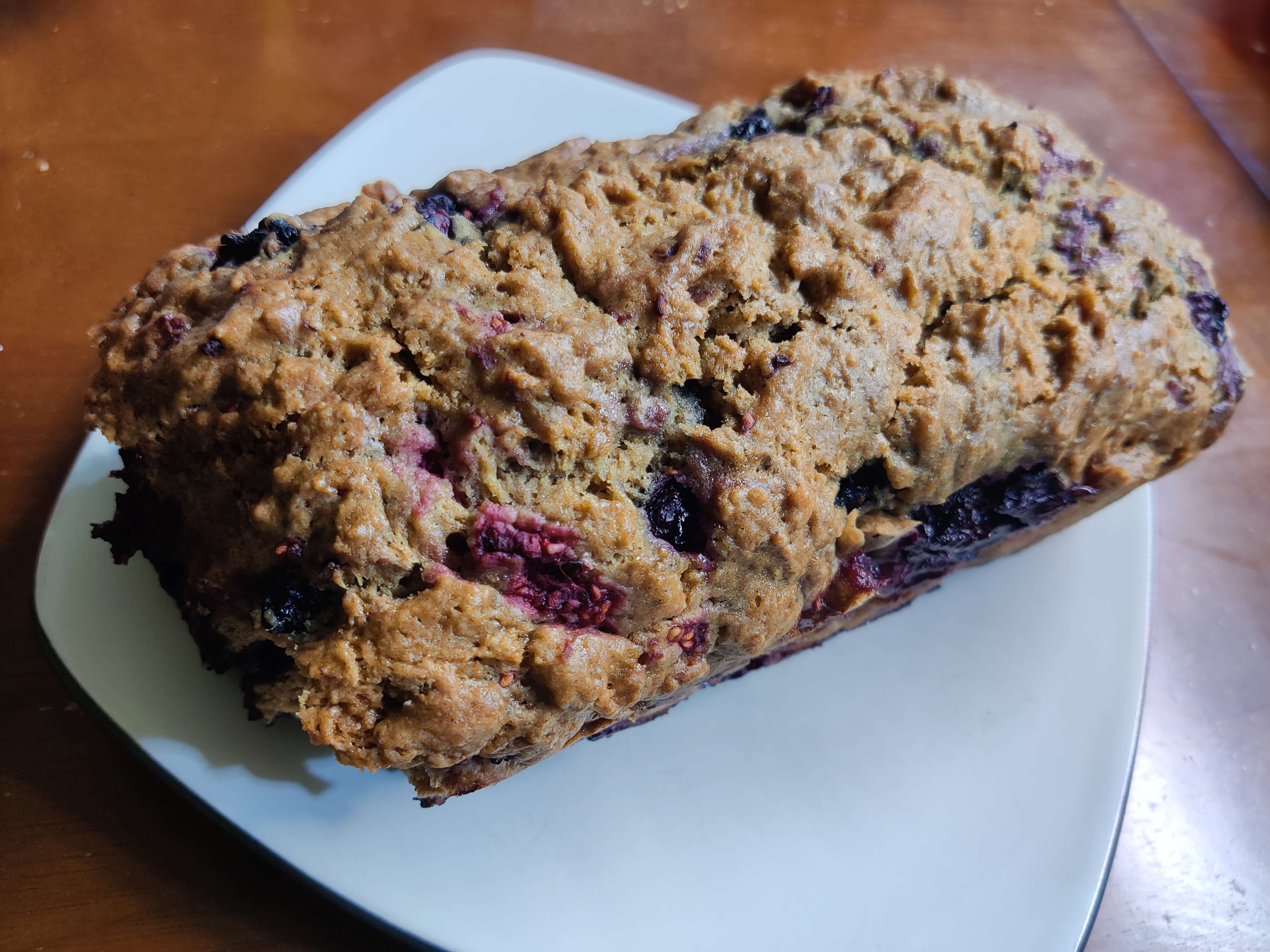 A craggy, golden brown loaf of bread with berries dotted throughout.